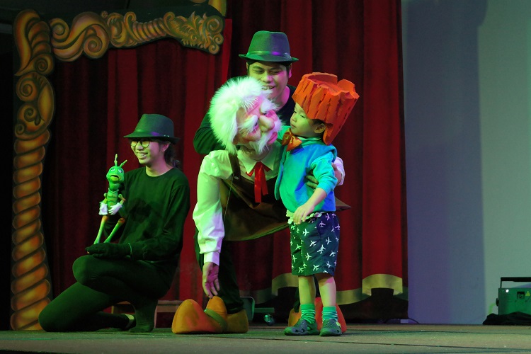 Pinocchio theatre presentation with old man puppet, a child, woman and a man on stage in Artbeatz